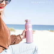 Woman sitting at the beach with pink diamond water bottle